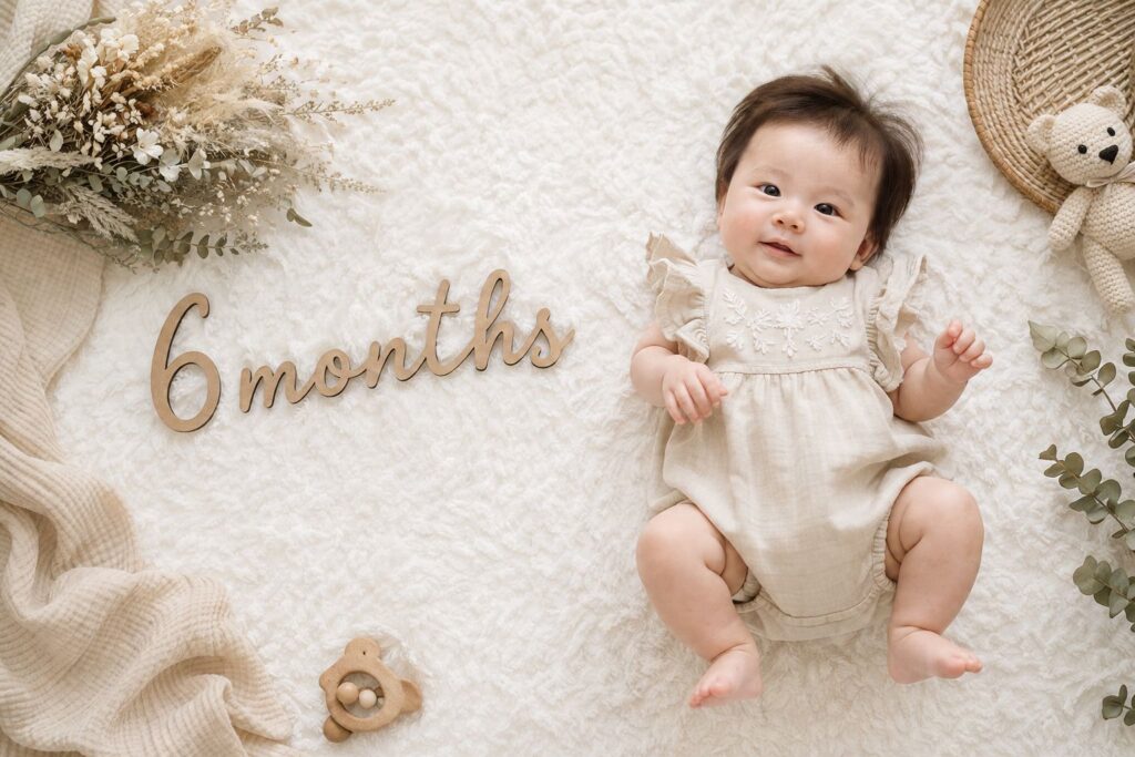 白いラグの上に寝かせた赤ちゃんと「6months」のレターバナー。ナチュラルで統一感のある色合い